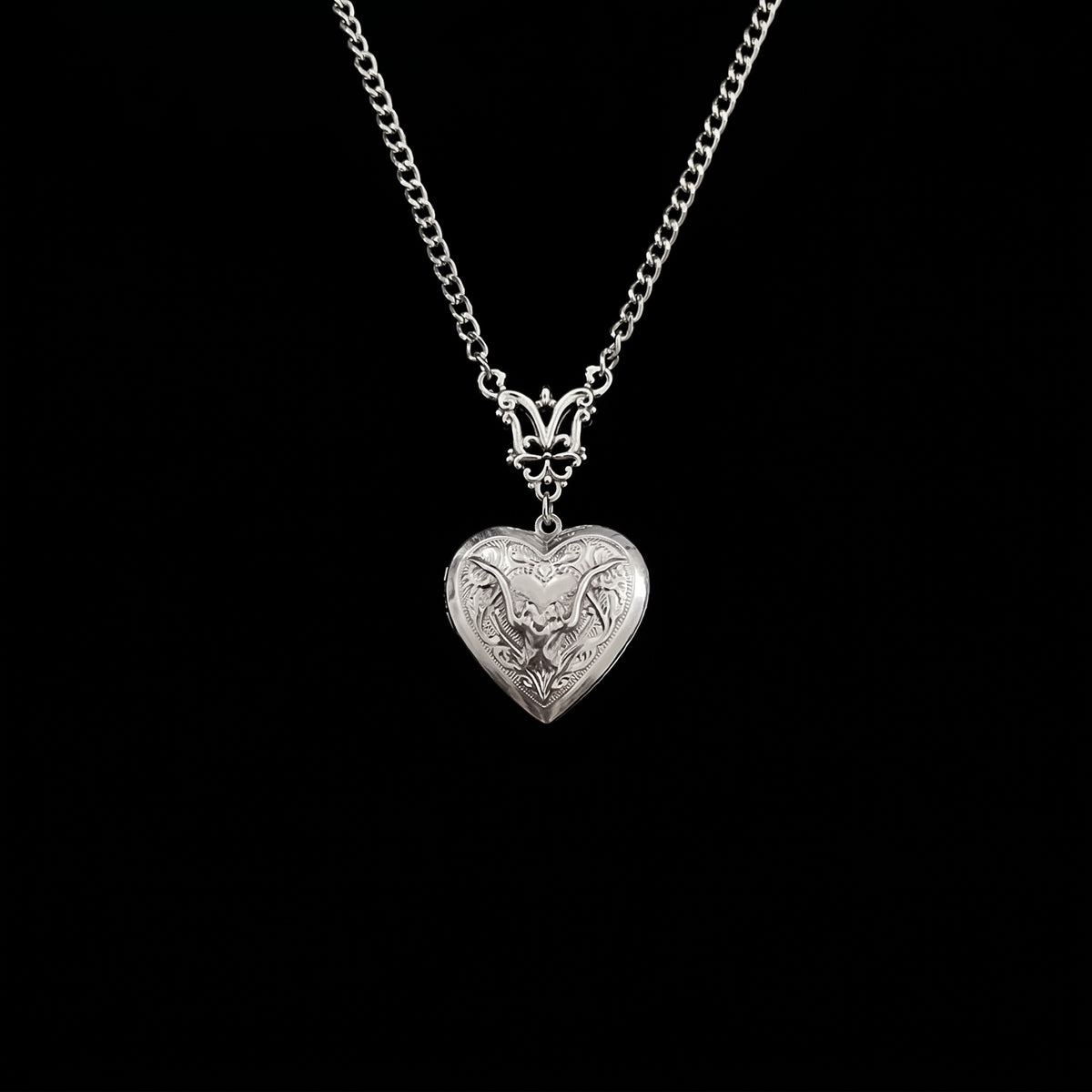 Ornate bat heart locket hanging on pure black background