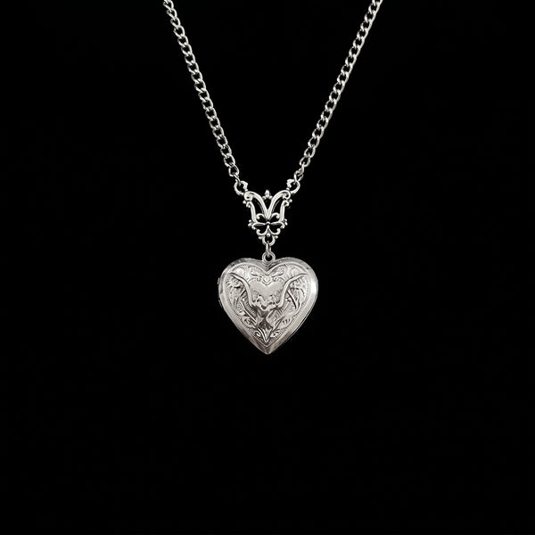 Ornate bat heart locket hanging on pure black background