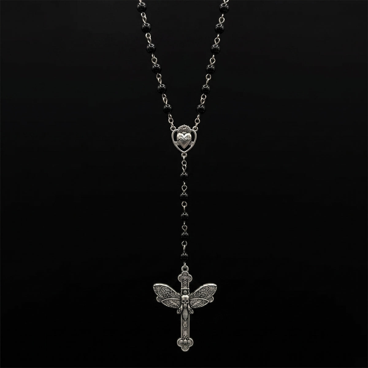Black bead rosary with silver cross hanging on pure black background
