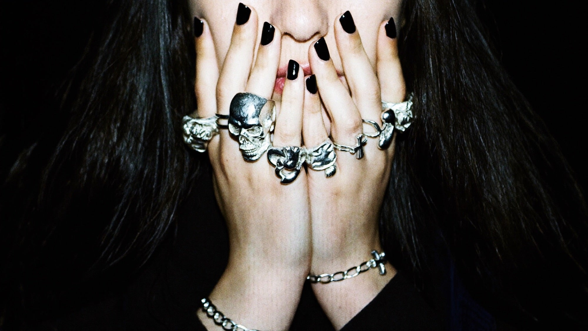 Hands stacked with silver rings crossed under chin